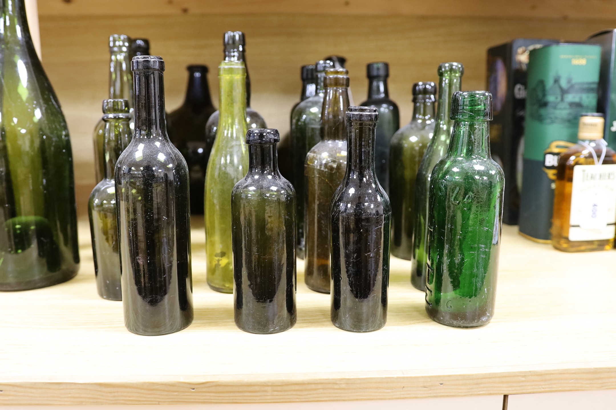 A pair of 18th century green glass onion bottles and a large quantity of other green glass bottles, tallest 38cm